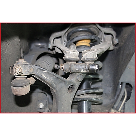 Nahaufnahme eines Fahrwerksteils: Schwarze Querlenker, Feder und Stoßdämpfer, gelbe Federung.